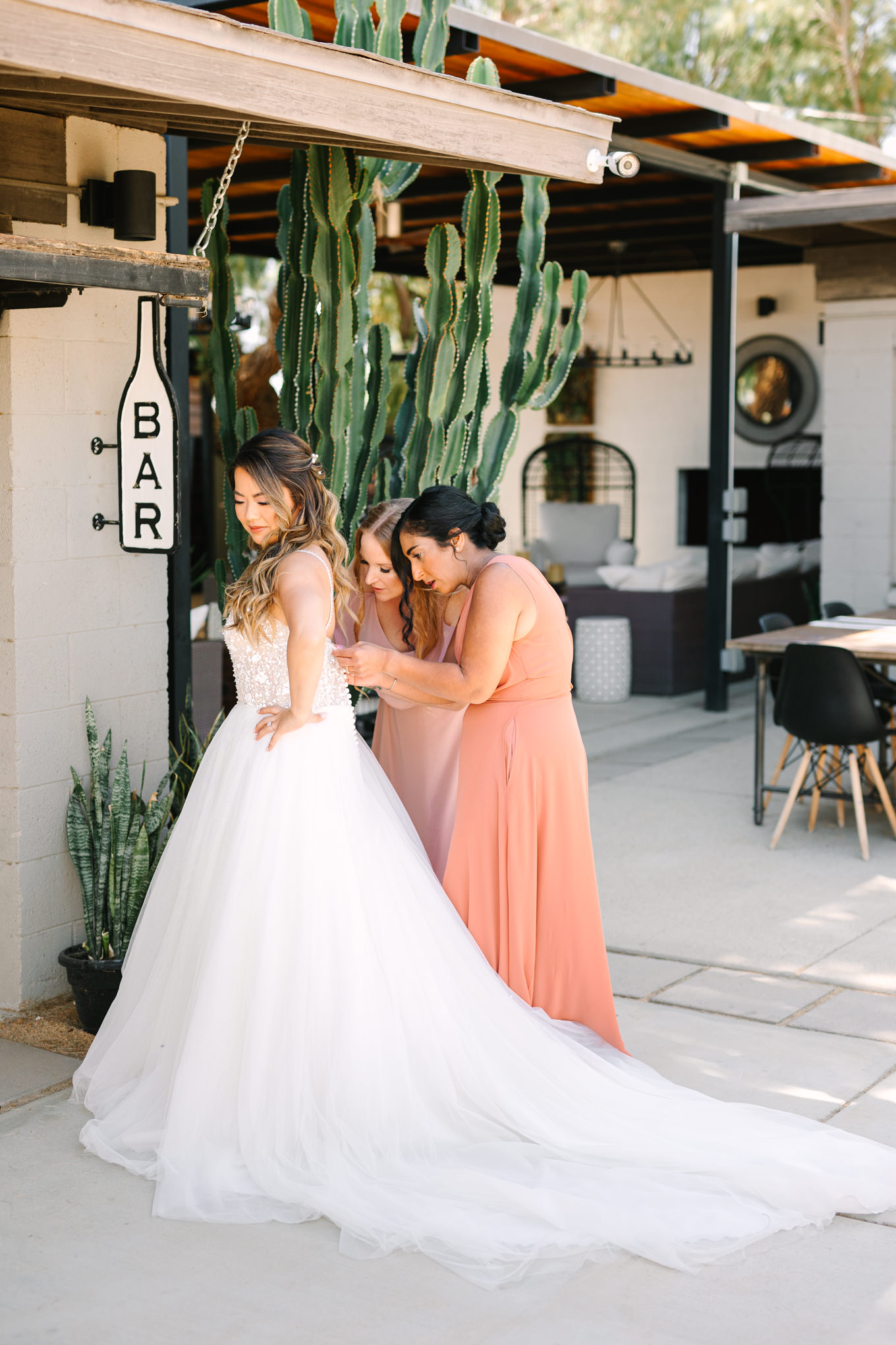 Bride getting dress on | Pink and orange Lautner Compound wedding | Colorful Palm Springs wedding photography | #palmspringsphotographer #palmspringswedding #lautnercompound #southerncaliforniawedding  Source: Mary Costa Photography | Los Angeles