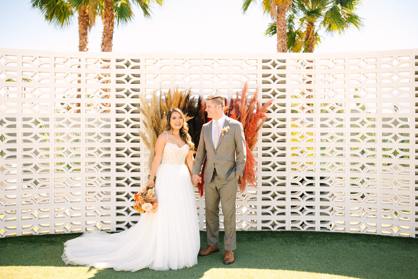 Bride and groom in front of breeze block wall | Pink and orange Lautner Compound wedding | Colorful Palm Springs wedding photography | #palmspringsphotographer #palmspringswedding #lautnercompound #southerncaliforniawedding  Source: Mary Costa Photography | Los Angeles