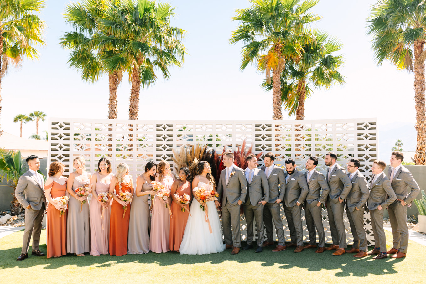 Wedding party on breeze block wall | Pink and orange Lautner Compound wedding | Colorful Palm Springs wedding photography | #palmspringsphotographer #palmspringswedding #lautnercompound #southerncaliforniawedding  Source: Mary Costa Photography | Los Angeles