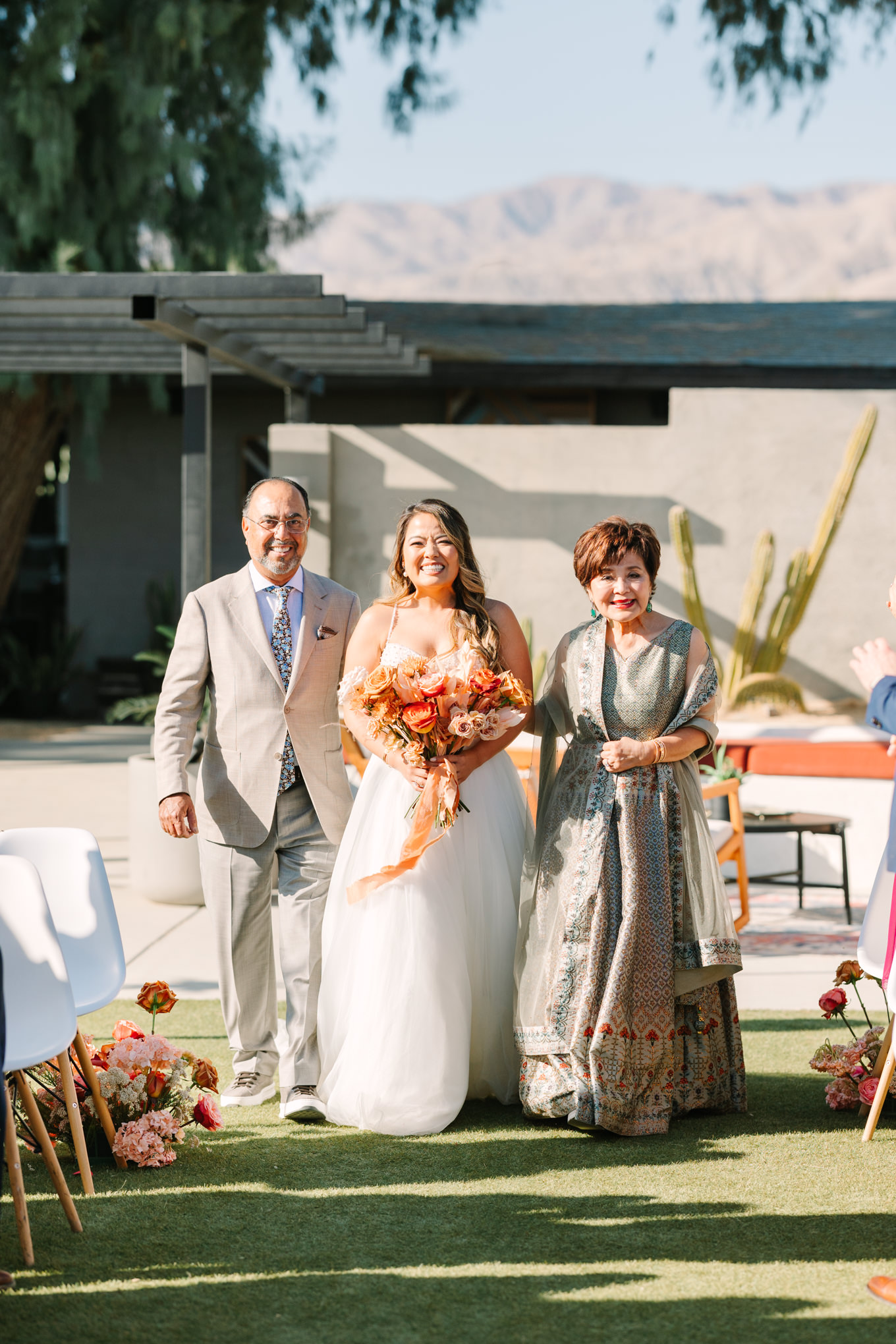 Bride walking with parents down the aisle | Pink and orange Lautner Compound wedding | Colorful Palm Springs wedding photography | #palmspringsphotographer #palmspringswedding #lautnercompound #southerncaliforniawedding  Source: Mary Costa Photography | Los Angeles