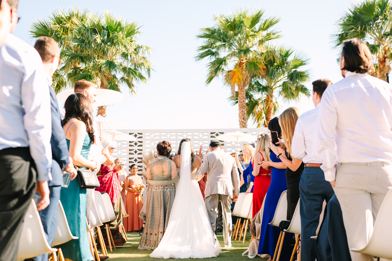 Bride walking down the aisle from the back | Pink and orange Lautner Compound wedding | Colorful Palm Springs wedding photography | #palmspringsphotographer #palmspringswedding #lautnercompound #southerncaliforniawedding  Source: Mary Costa Photography | Los Angeles