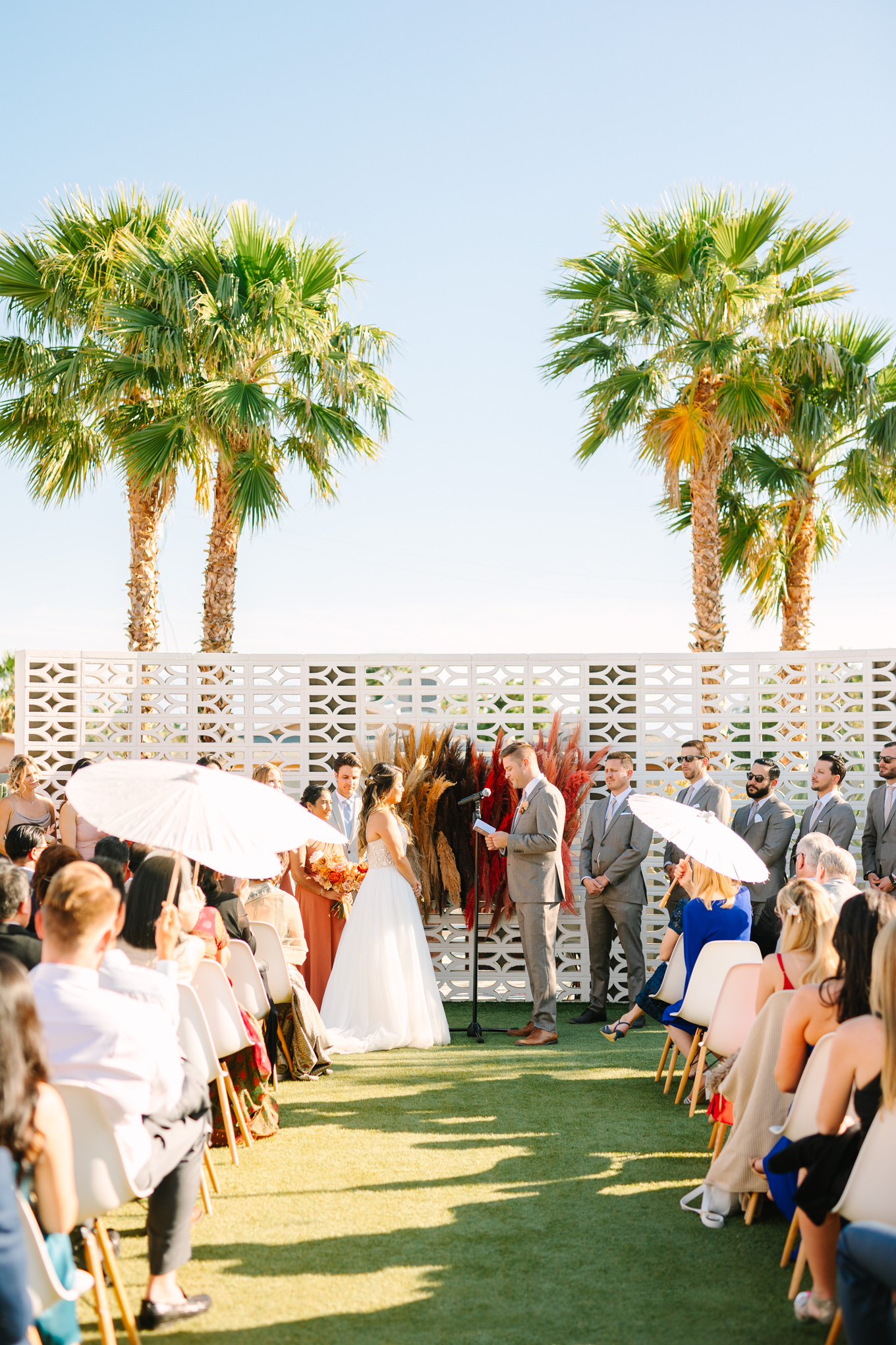 Wedding ceremony among palm trees | Pink and orange Lautner Compound wedding | Colorful Palm Springs wedding photography | #palmspringsphotographer #palmspringswedding #lautnercompound #southerncaliforniawedding  Source: Mary Costa Photography | Los Angeles