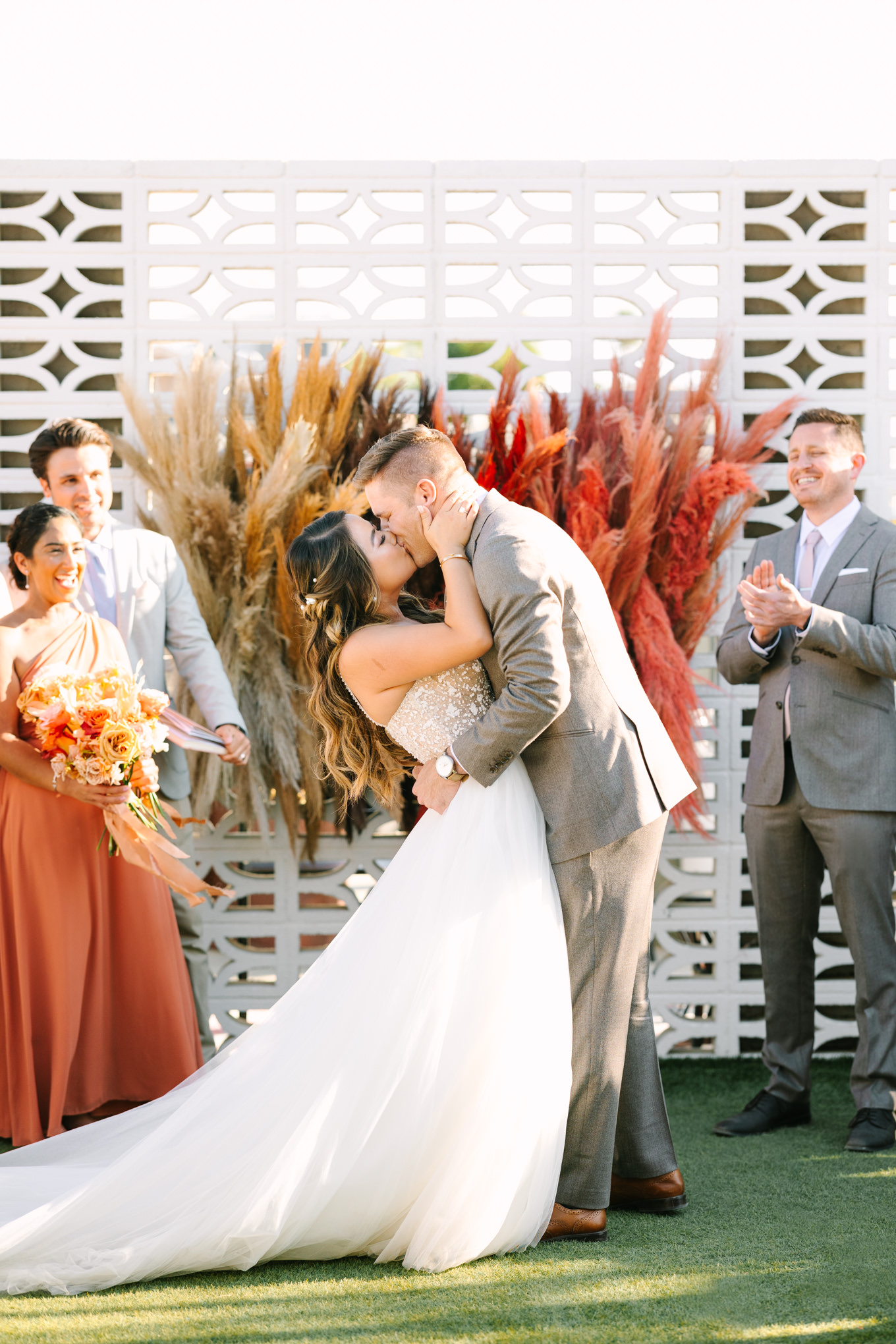 Bride and groom kissing at wedding ceremony | Pink and orange Lautner Compound wedding | Colorful Palm Springs wedding photography | #palmspringsphotographer #palmspringswedding #lautnercompound #southerncaliforniawedding  Source: Mary Costa Photography | Los Angeles