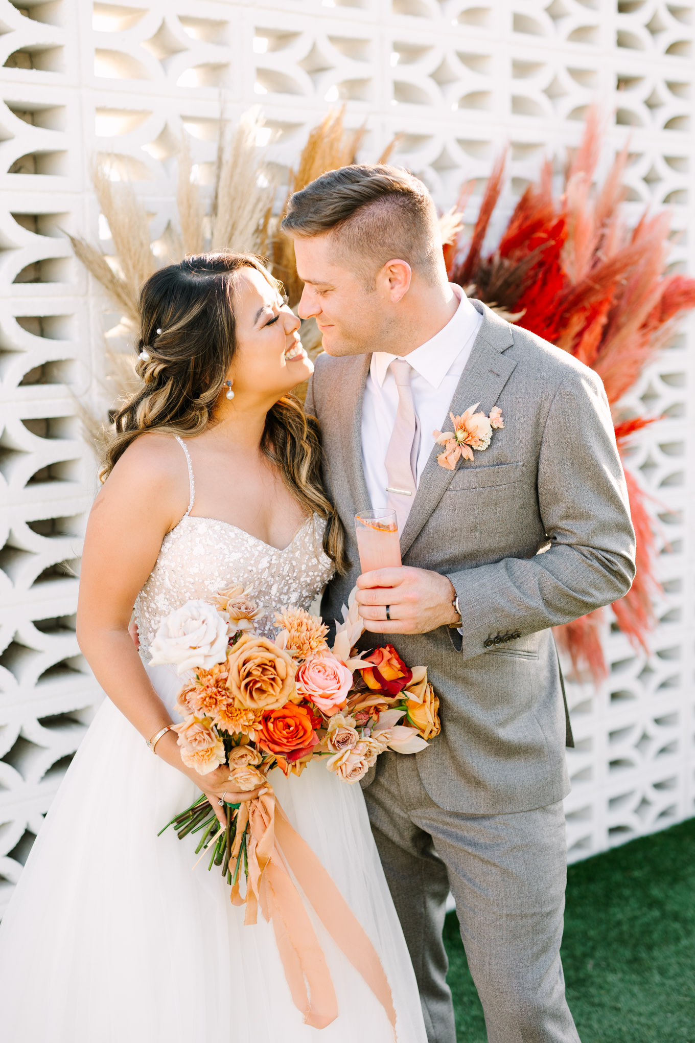 Bride and groom on white breeze block wall | Pink and orange Lautner Compound wedding | Colorful Palm Springs wedding photography | #palmspringsphotographer #palmspringswedding #lautnercompound #southerncaliforniawedding  Source: Mary Costa Photography | Los Angeles