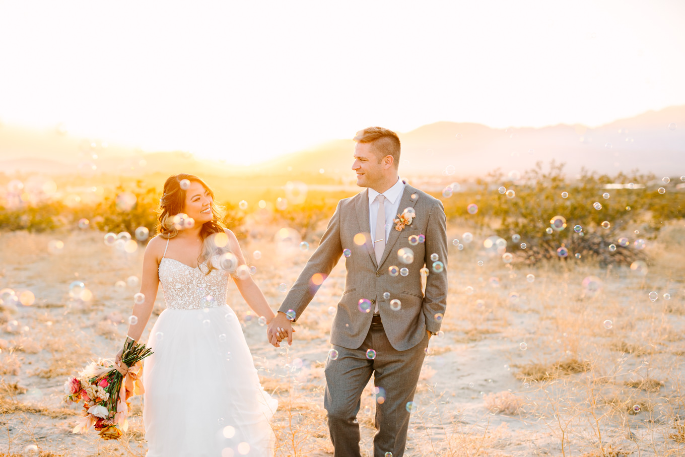 Bride and groom in the desert at sunset with bubbles | Pink and orange Lautner Compound wedding | Colorful Palm Springs wedding photography | #palmspringsphotographer #palmspringswedding #lautnercompound #southerncaliforniawedding  Source: Mary Costa Photography | Los Angeles