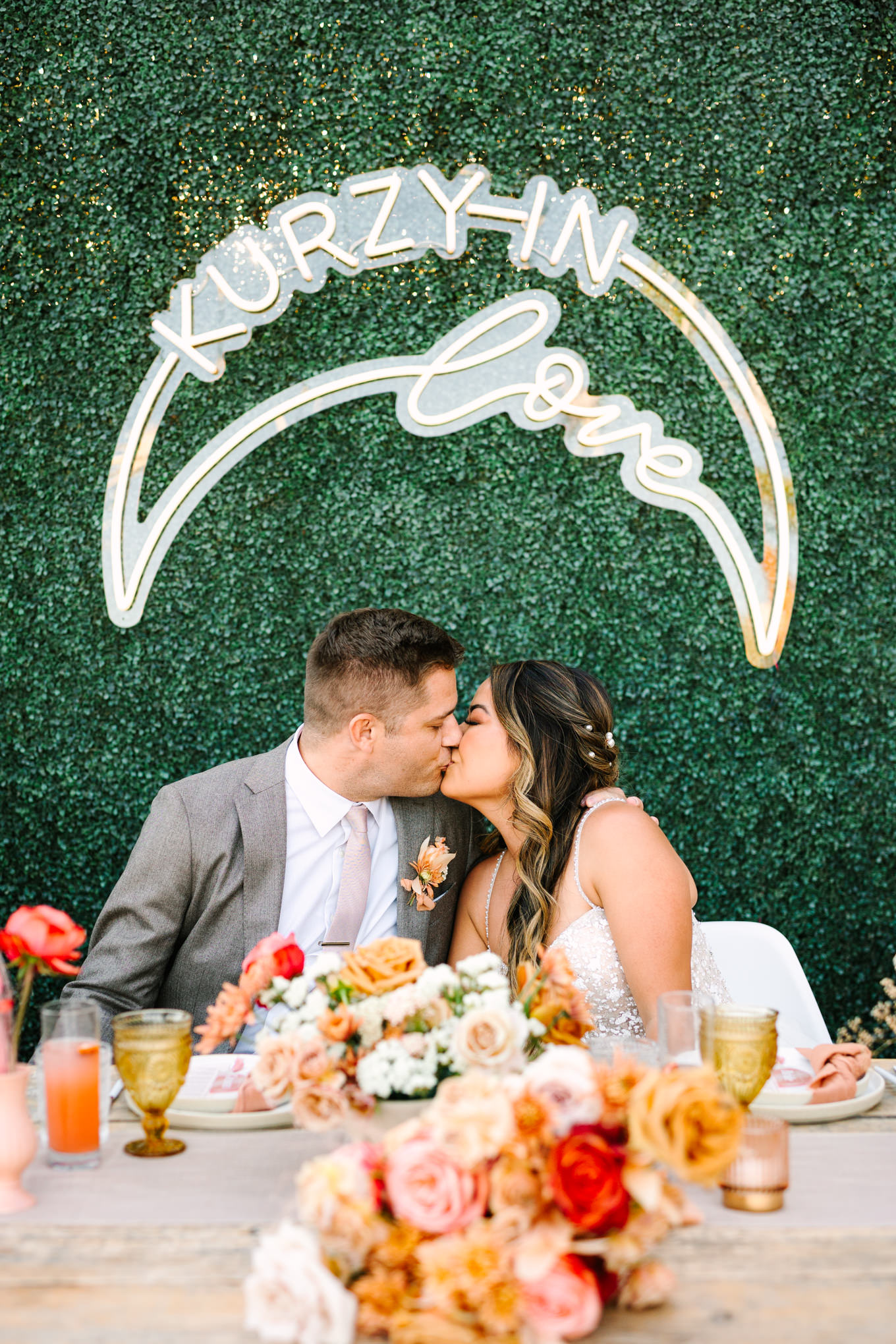 Bride and groom kissing with custom neon sign | Pink and orange Lautner Compound wedding | Colorful Palm Springs wedding photography | #palmspringsphotographer #palmspringswedding #lautnercompound #southerncaliforniawedding  Source: Mary Costa Photography | Los Angeles