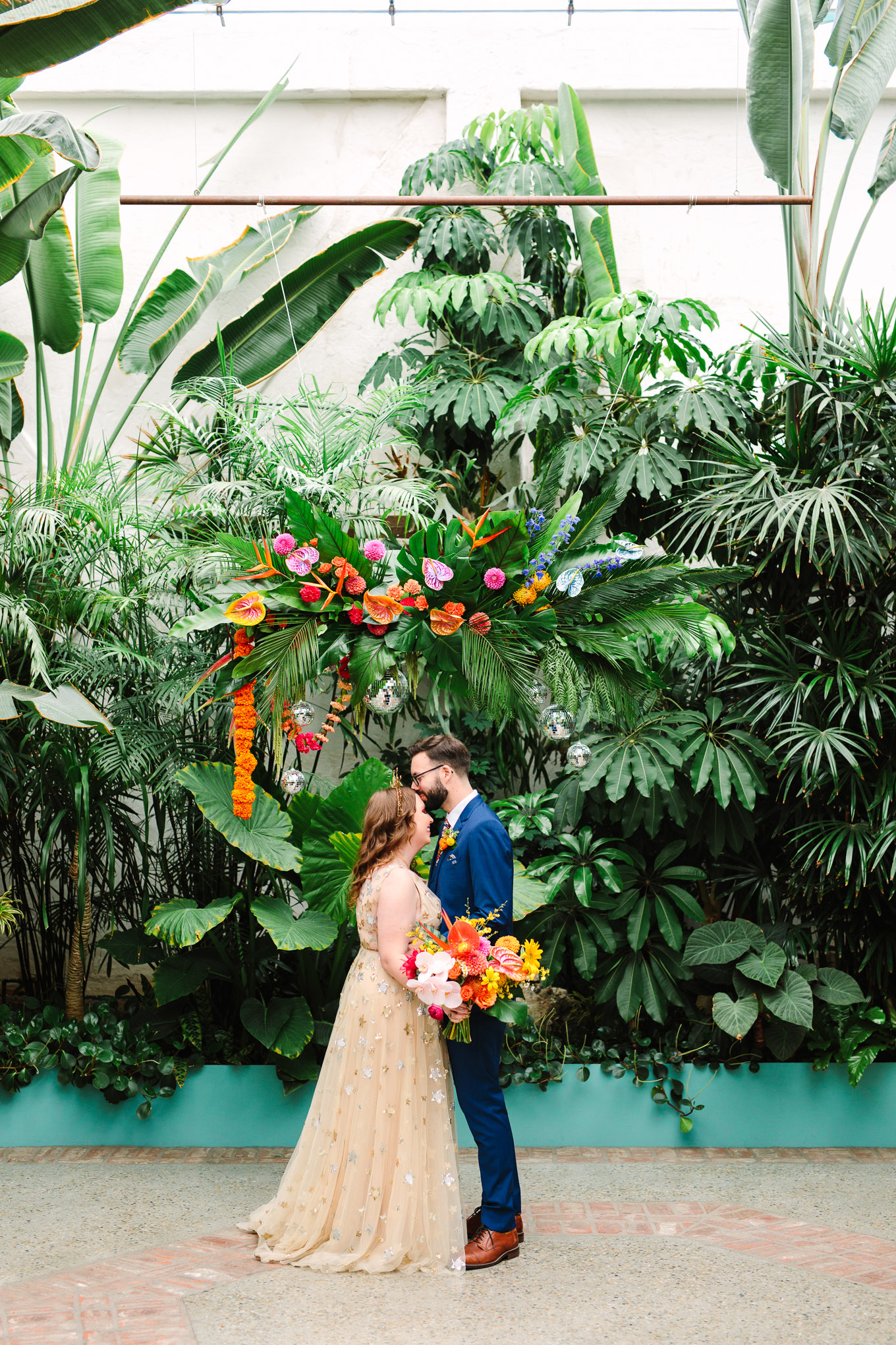 Bride and groom in front of tropical plants and colorful ceremony backdrop | Colorful Downtown Los Angeles Valentine Wedding | Los Angeles wedding photographer | #losangeleswedding #colorfulwedding #DTLA #valentinedtla   Source: Mary Costa Photography | Los Angeles