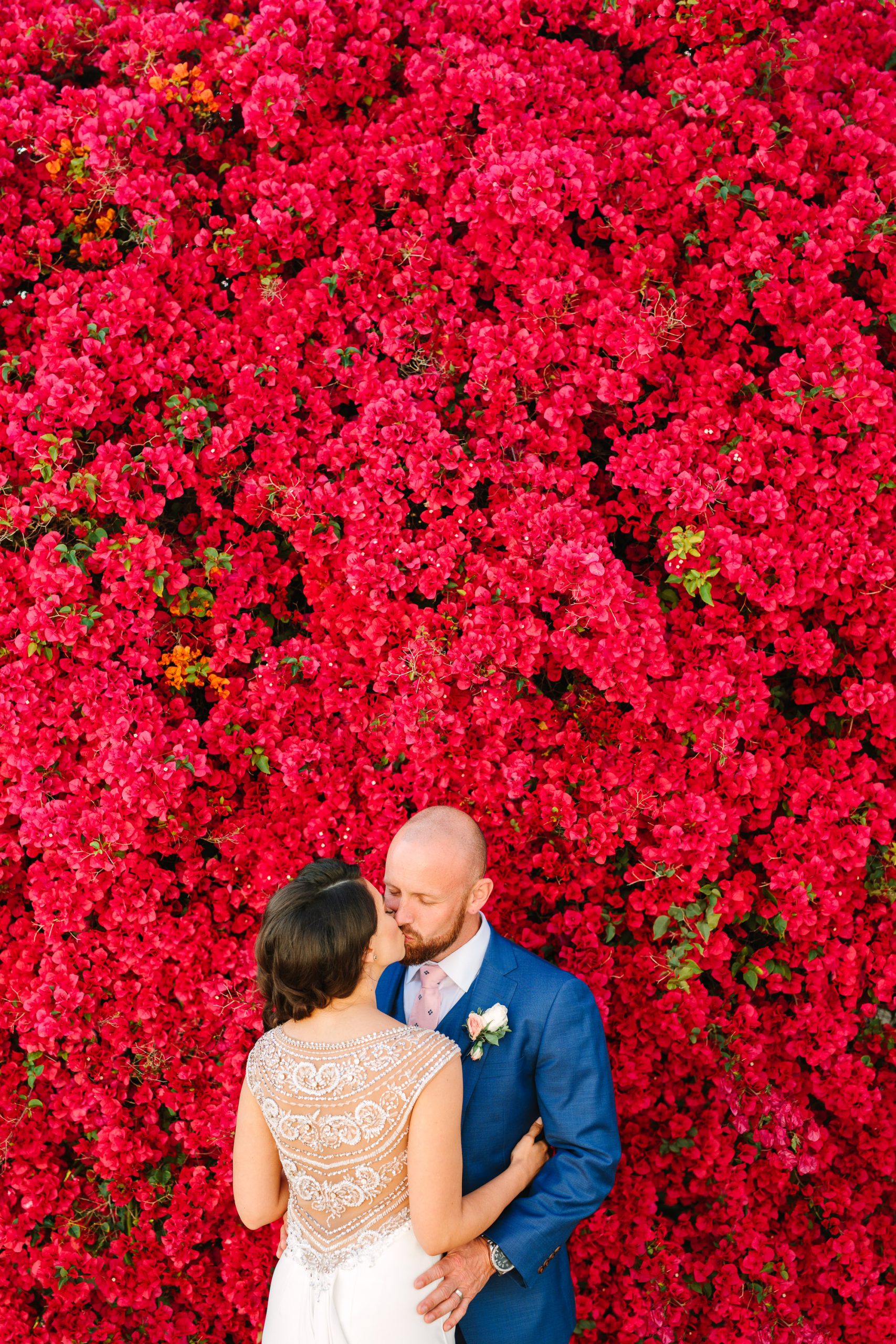 Couple kissing by blooming bougainvillea by Mary Costa Photography