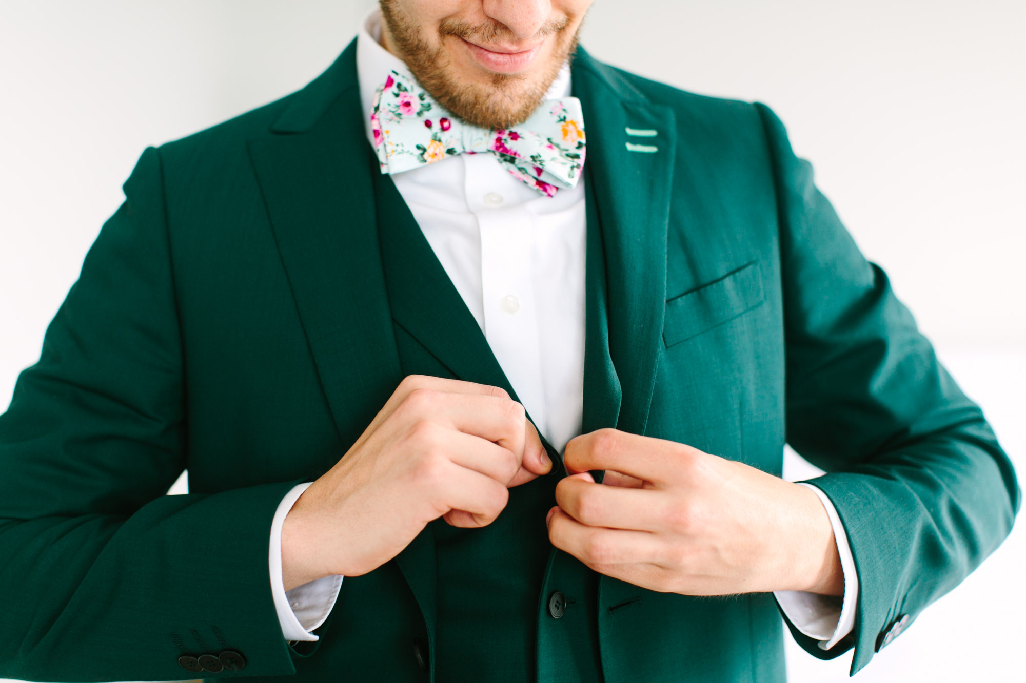 Groom getting ready in emerald tux by Mary Costa Photography