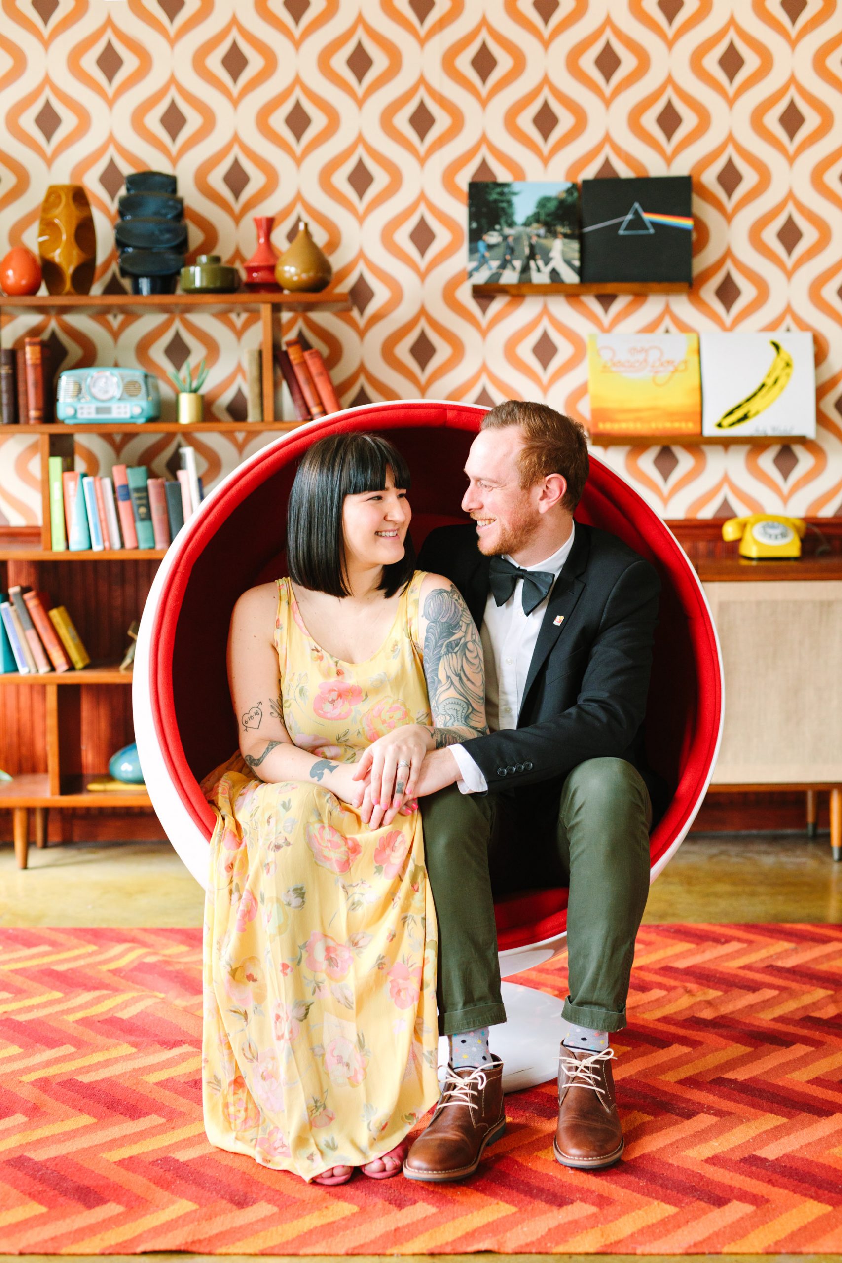 Couple in round chair surrounded by retro decor www.marycostaweddings.com