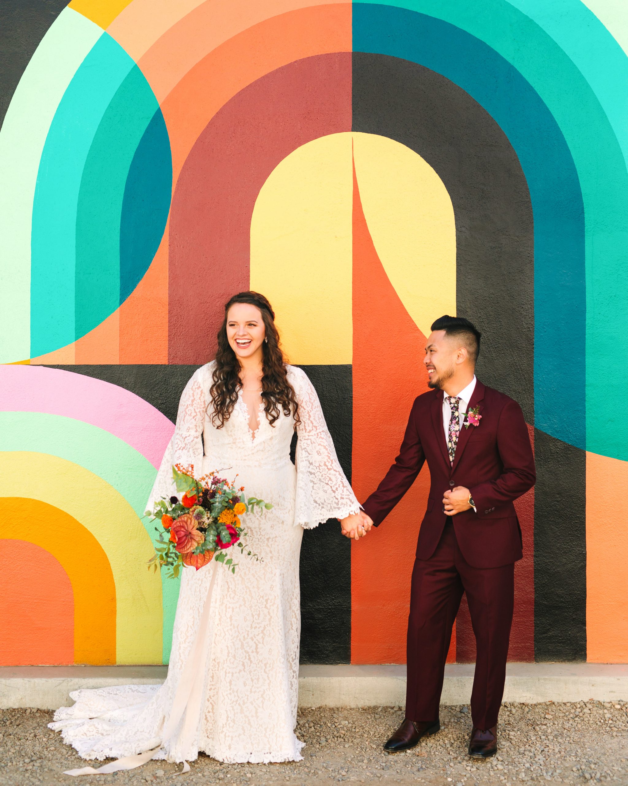 Bride and groom in front of colorful mural