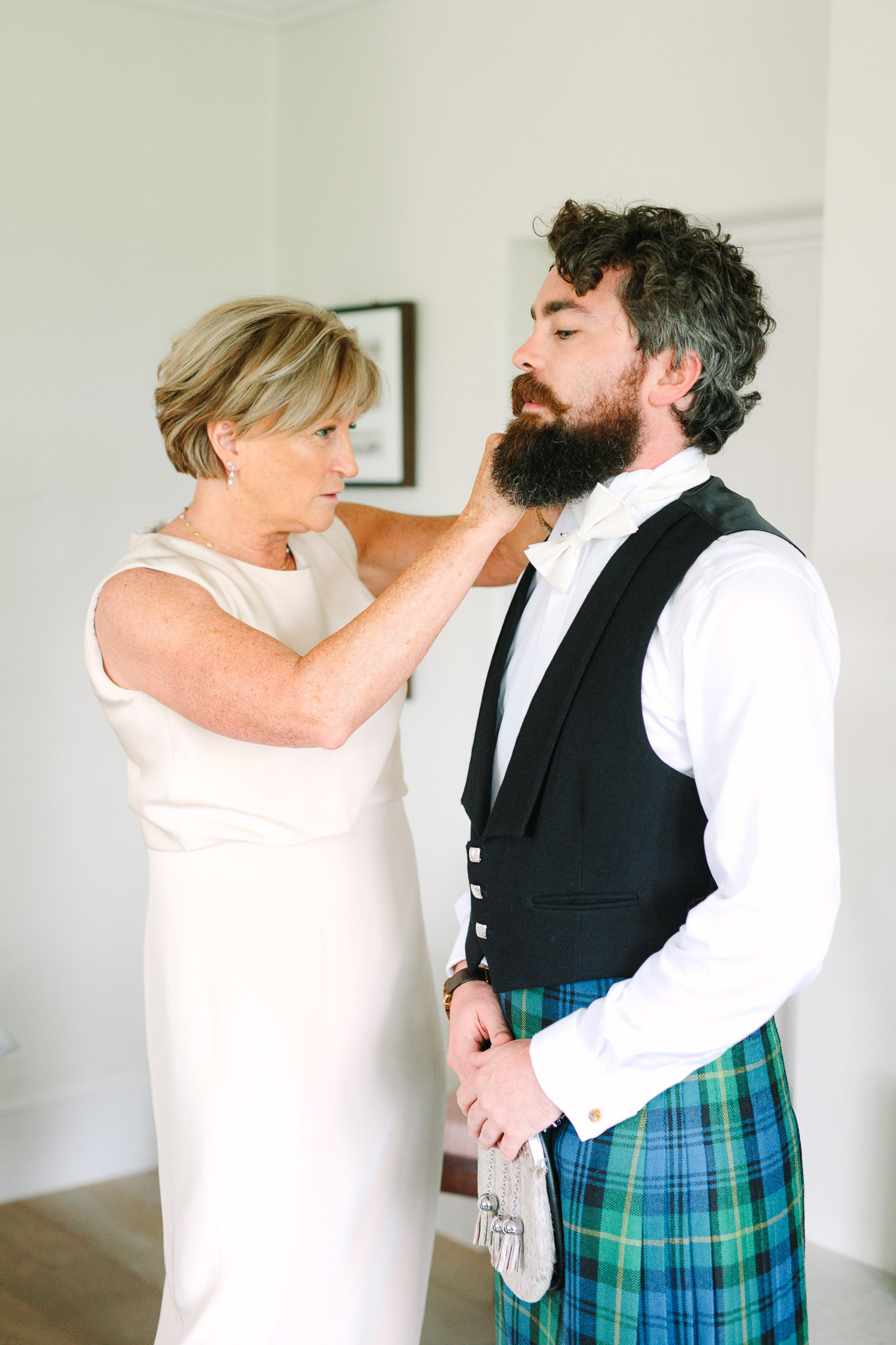 Mother of the bride helping son dress in traditional Scottish kilt. Millbrook Resort Queenstown New Zealand wedding by Mary Costa Photography | www.marycostaweddings.com