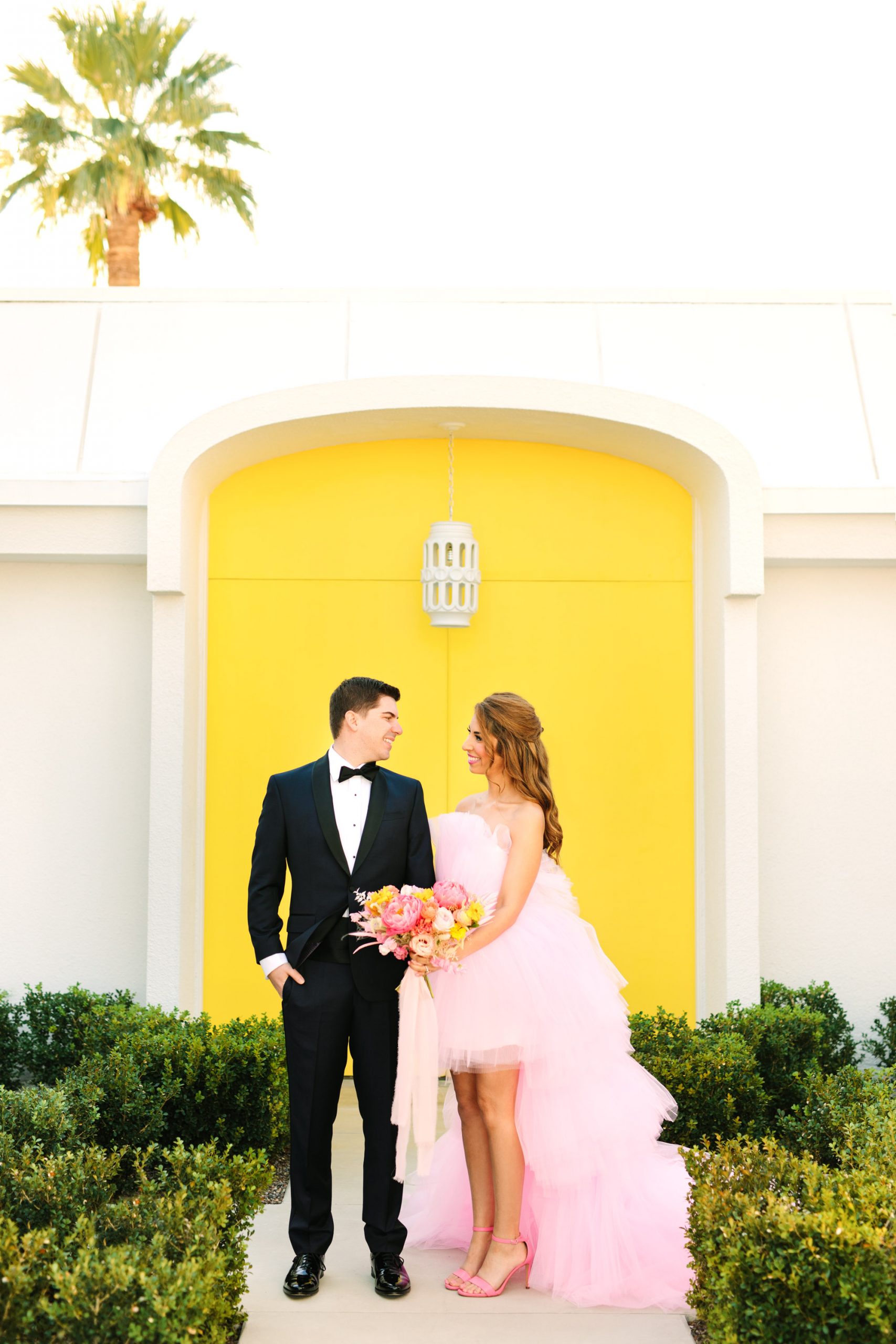 Pink wedding dress Palm Springs elopement featured on Green Wedding Shoes | Colorful mid-century modern wedding with bright yellow door backdrop | Vibrant and elevated wedding photos for fun-loving couples in Southern California #palmspringswedding #palmspringselopement #pinkwedding #greenweddingshoes Source: Mary Costa Photography | Los Angeles