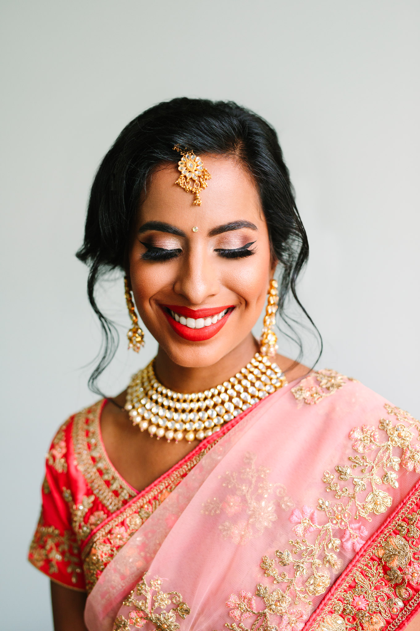 Smiling bride in bright red lipstick. Two Disney artists create a unique and colorful Indian Fusion wedding at The Fig House Los Angeles, featured on Green Wedding Shoes. | Colorful and elevated wedding inspiration for fun-loving couples in Southern California | #indianwedding #indianfusionwedding #thefighouse #losangeleswedding   Source: Mary Costa Photography | Los Angeles