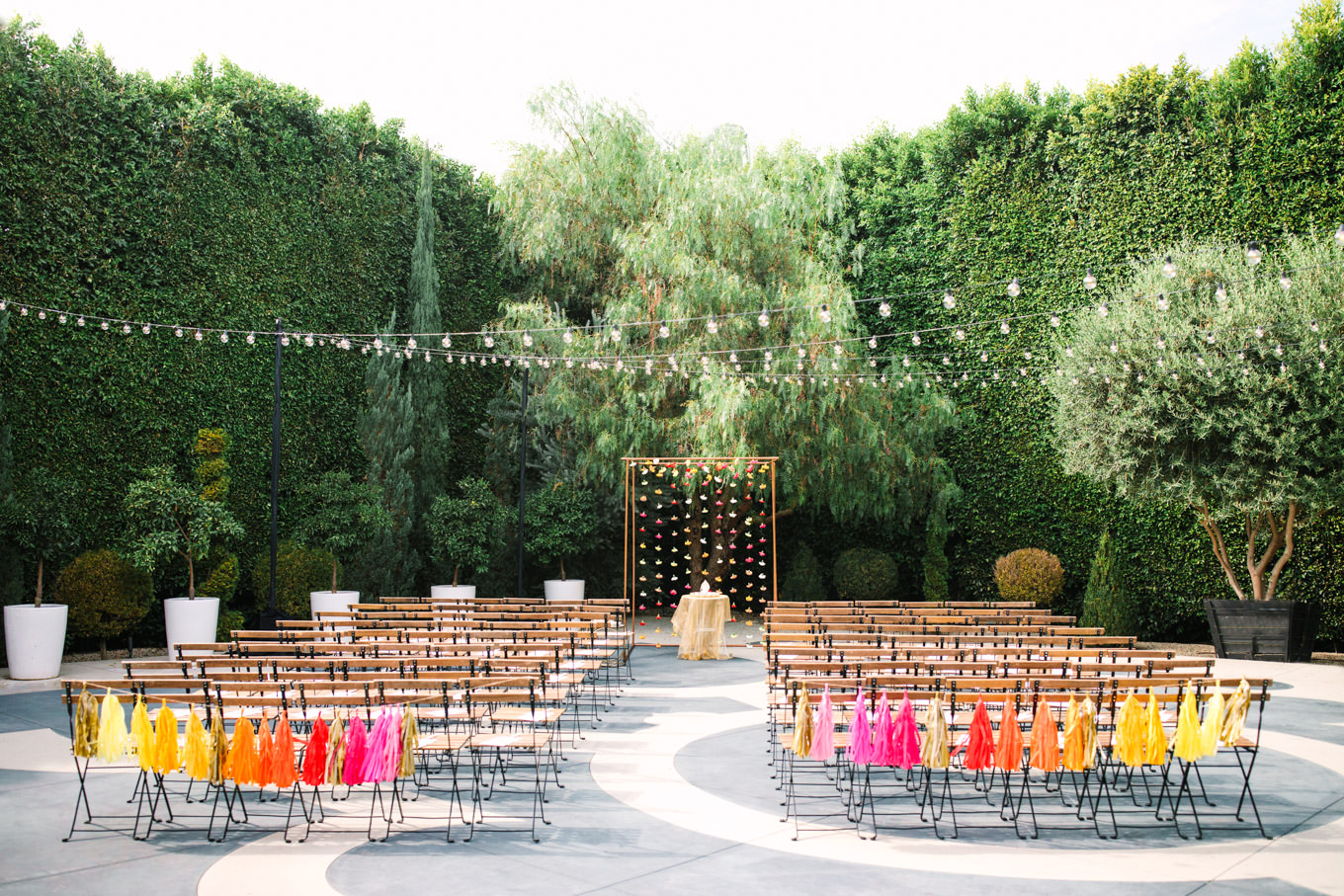 Colorful seat tassels for outdoor ceremony. Two Disney artists create a unique and colorful Indian Fusion wedding at The Fig House Los Angeles, featured on Green Wedding Shoes. | Colorful and elevated wedding inspiration for fun-loving couples in Southern California | #indianwedding #indianfusionwedding #thefighouse #losangeleswedding   Source: Mary Costa Photography | Los Angeles