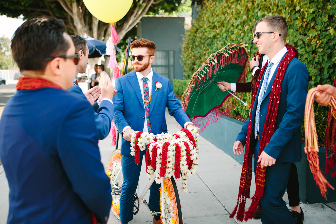 Groom riding into wedding ceremony on white Baraat bicycle. Two Disney artists create a unique and colorful Indian Fusion wedding at The Fig House Los Angeles, featured on Green Wedding Shoes. | Colorful and elevated wedding inspiration for fun-loving couples in Southern California | #indianwedding #indianfusionwedding #thefighouse #losangeleswedding   Source: Mary Costa Photography | Los Angeles