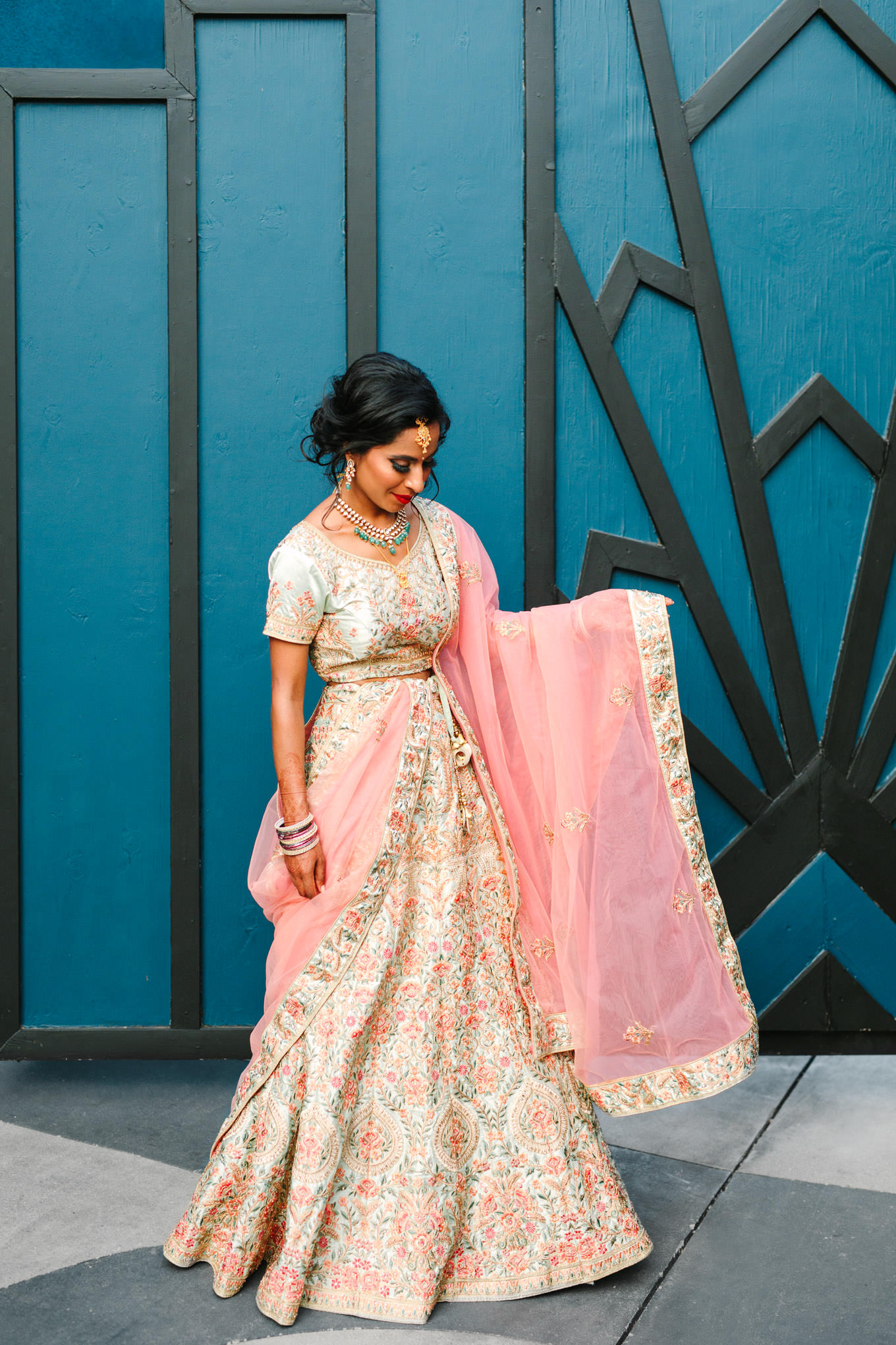 Bride in embroidered pink and cream gown outside of venue. Two Disney artists create a unique and colorful Indian Fusion wedding at The Fig House Los Angeles, featured on Green Wedding Shoes. | Colorful and elevated wedding inspiration for fun-loving couples in Southern California | #indianwedding #indianfusionwedding #thefighouse #losangeleswedding   Source: Mary Costa Photography | Los Angeles