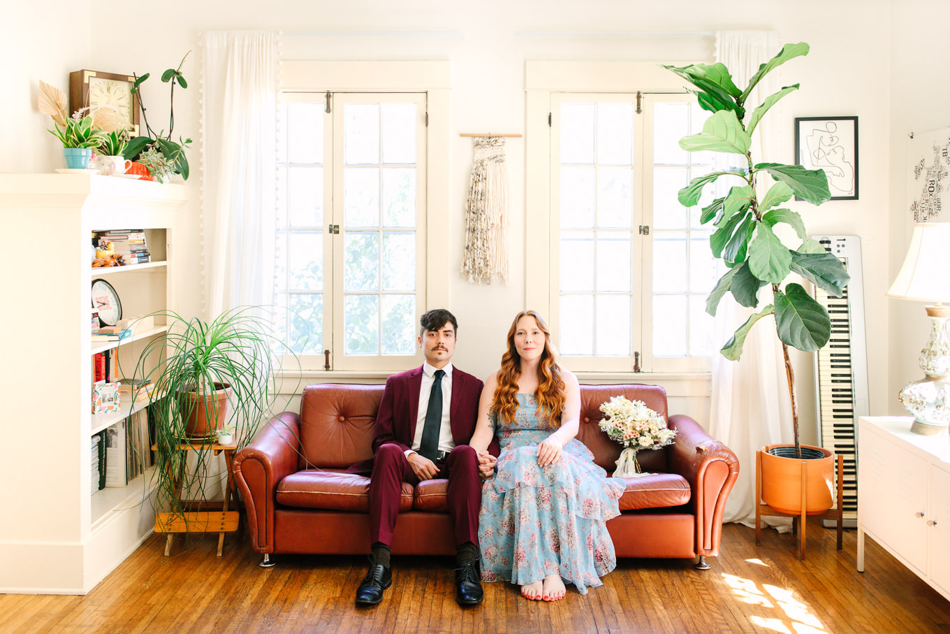 Couple sitting on leather couch in boho living room with plants | Los Angeles Arboretum Elopement | Colorful and elevated wedding photography for fun-loving couples in Southern California | #LosAngelesElopement #elopement #LAarboretum #LAskyline #elopementphotos   Source: Mary Costa Photography | Los Angeles