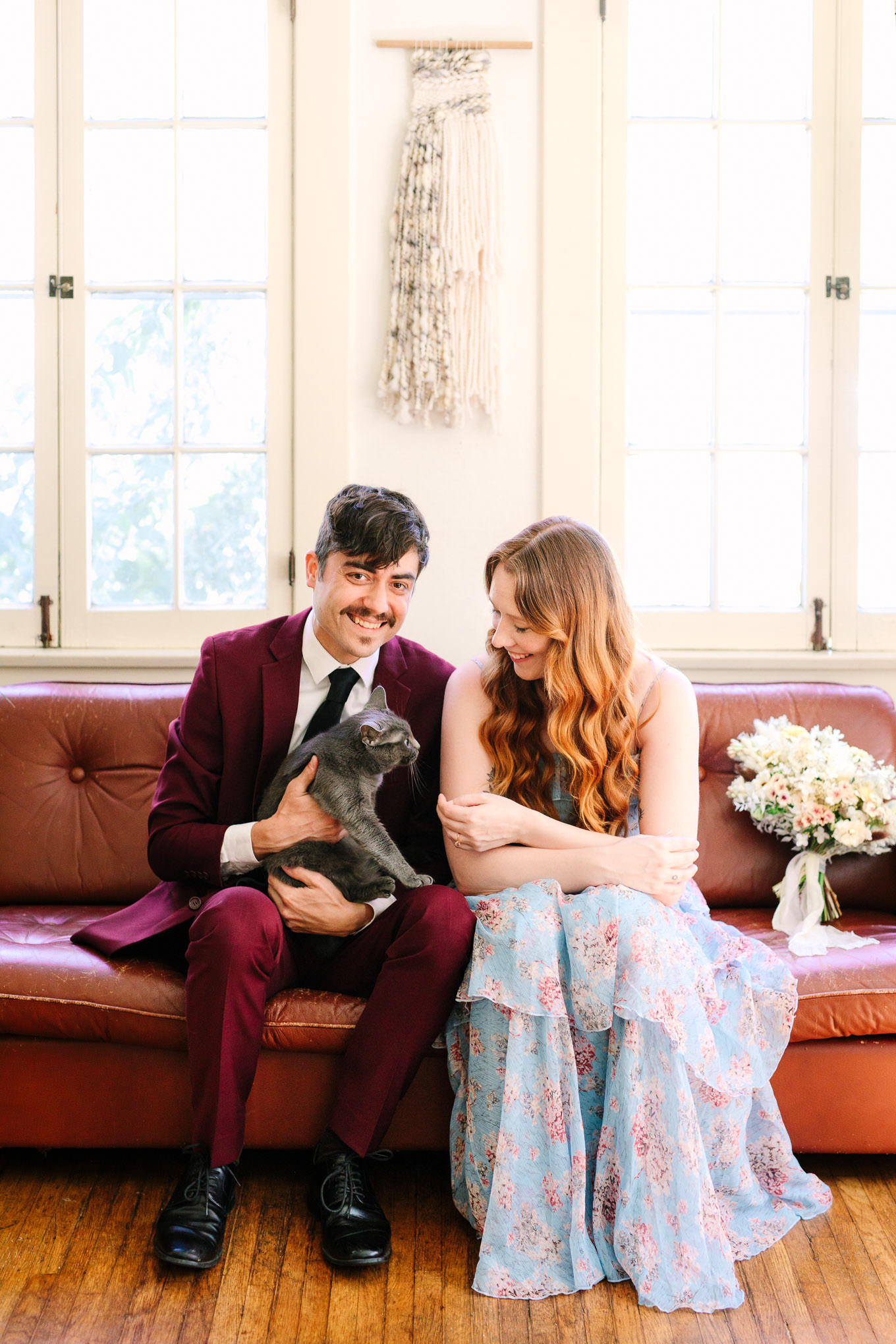 Couple with their gray cat on the couch | Los Angeles Arboretum Elopement | Colorful and elevated wedding photography for fun-loving couples in Southern California | #LosAngelesElopement #elopement #LAarboretum #LAskyline #elopementphotos   Source: Mary Costa Photography | Los Angeles