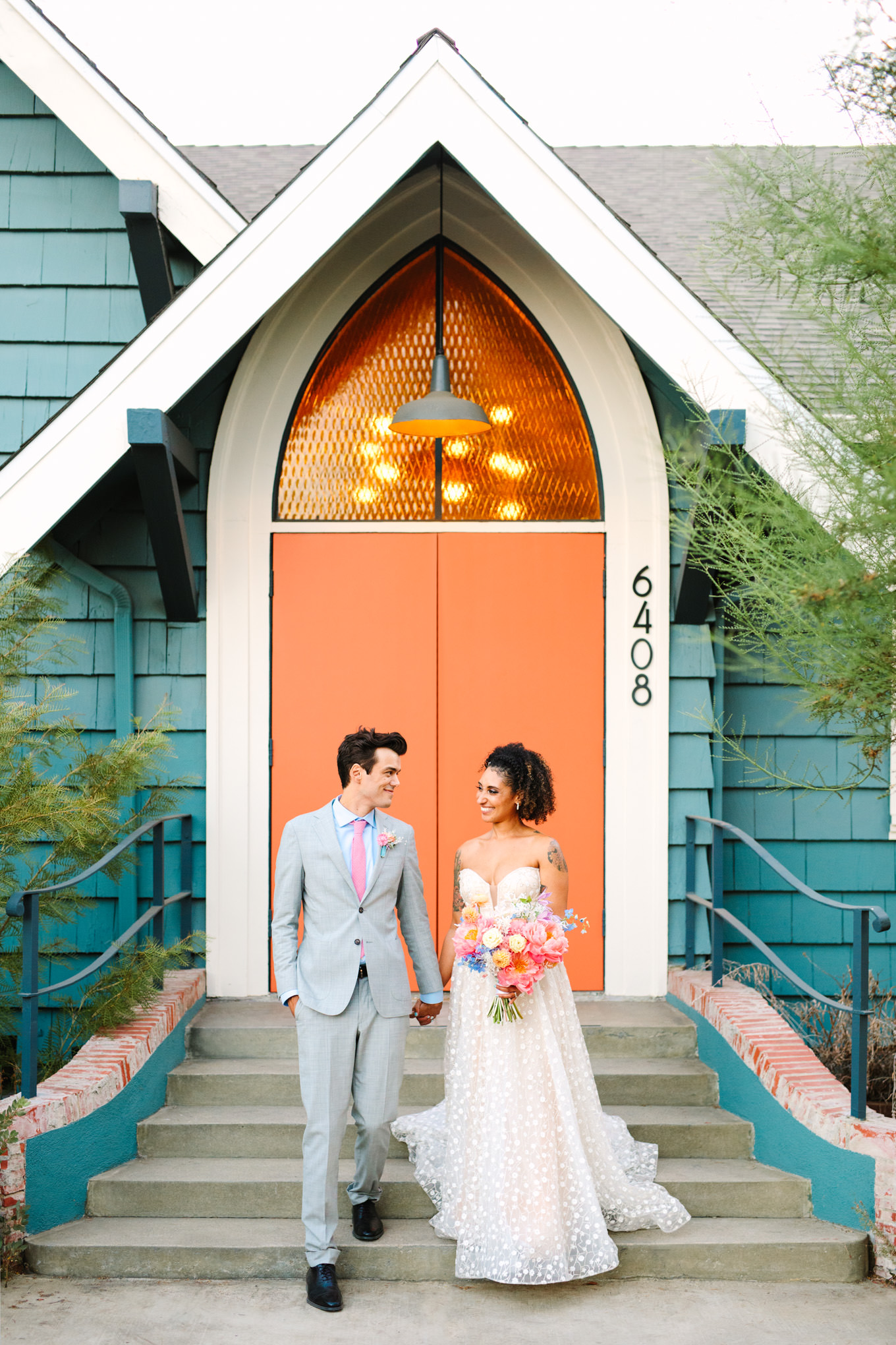 Wedding portrait in front of orange door | Colorful pop-up micro wedding at The Ruby Street Los Angeles featured on Green Wedding Shoes | Colorful and elevated photography for fun-loving couples in Southern California | #colorfulwedding #popupwedding #weddingphotography #microwedding Source: Mary Costa Photography | Los Angeles