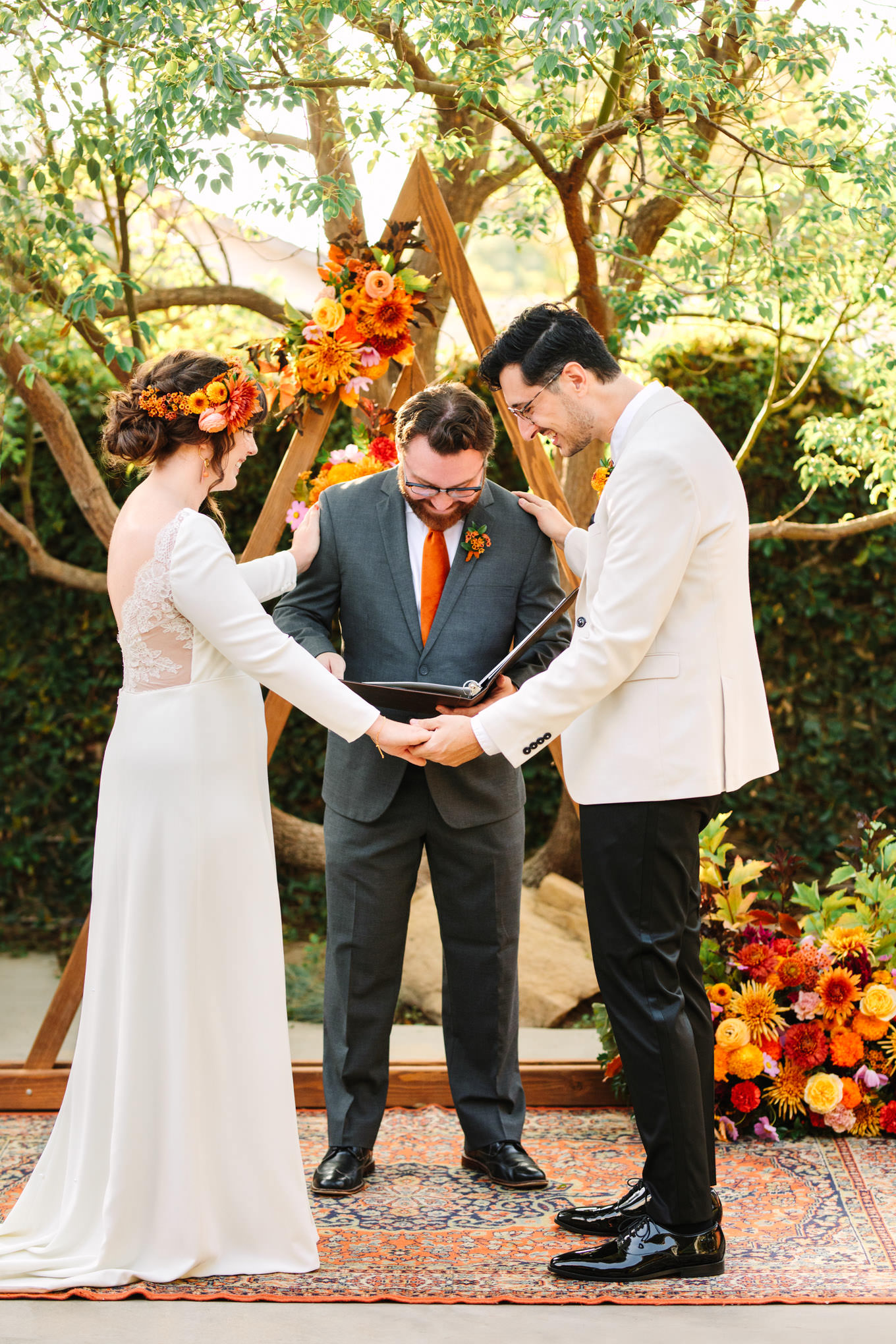 Bride and groom and officiant in prayer | Vibrant backyard micro wedding featured on Green Wedding Shoes | Colorful LA wedding photography | #losangeleswedding #backyardwedding #microwedding #laweddingphotographer Source: Mary Costa Photography | Los Angeles