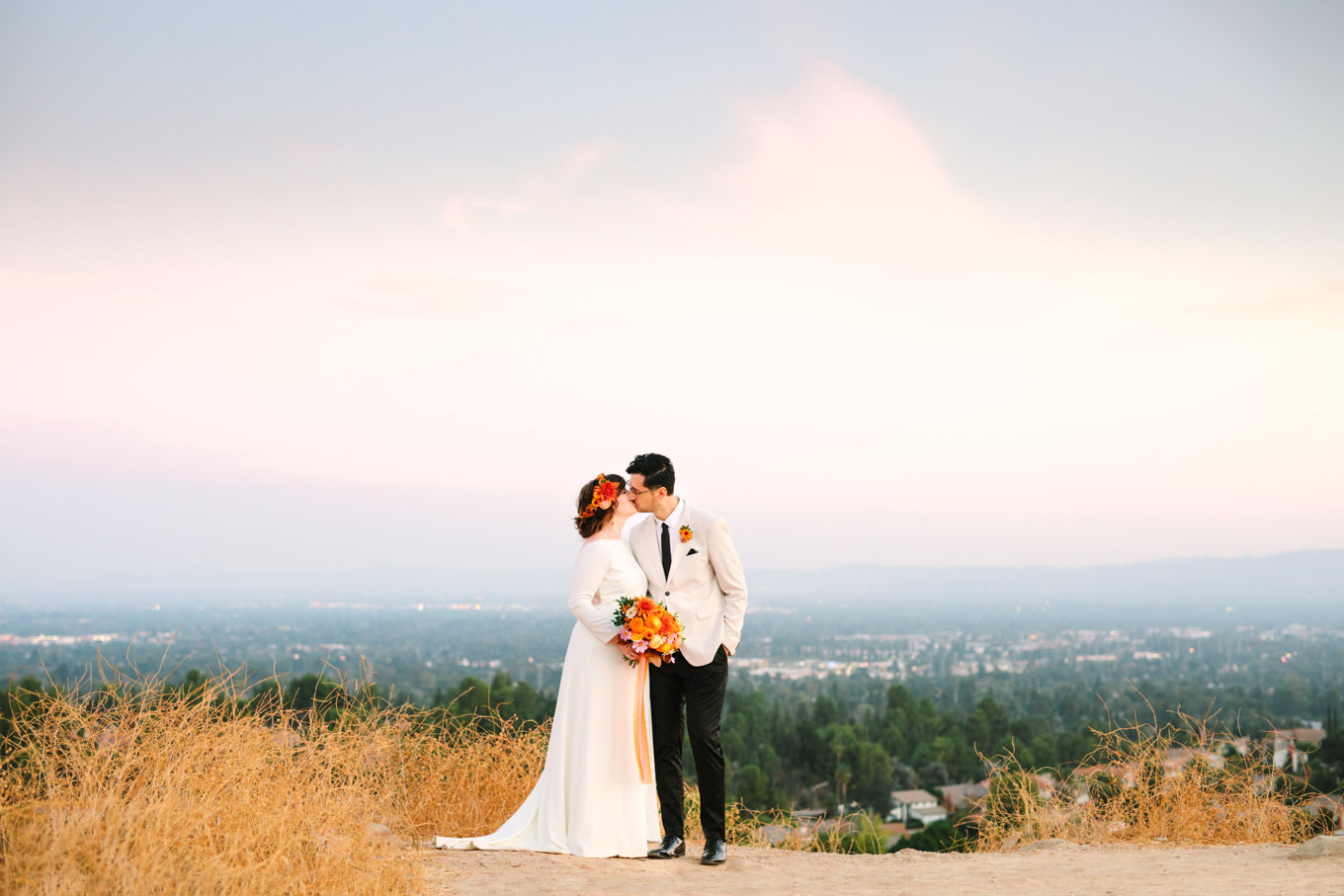 Bride and groom share a kiss with incredible views. | Vibrant backyard micro wedding featured on Green Wedding Shoes | Colorful LA wedding photography | #losangeleswedding #backyardwedding #microwedding #laweddingphotographer Source: Mary Costa Photography | Los Angeles