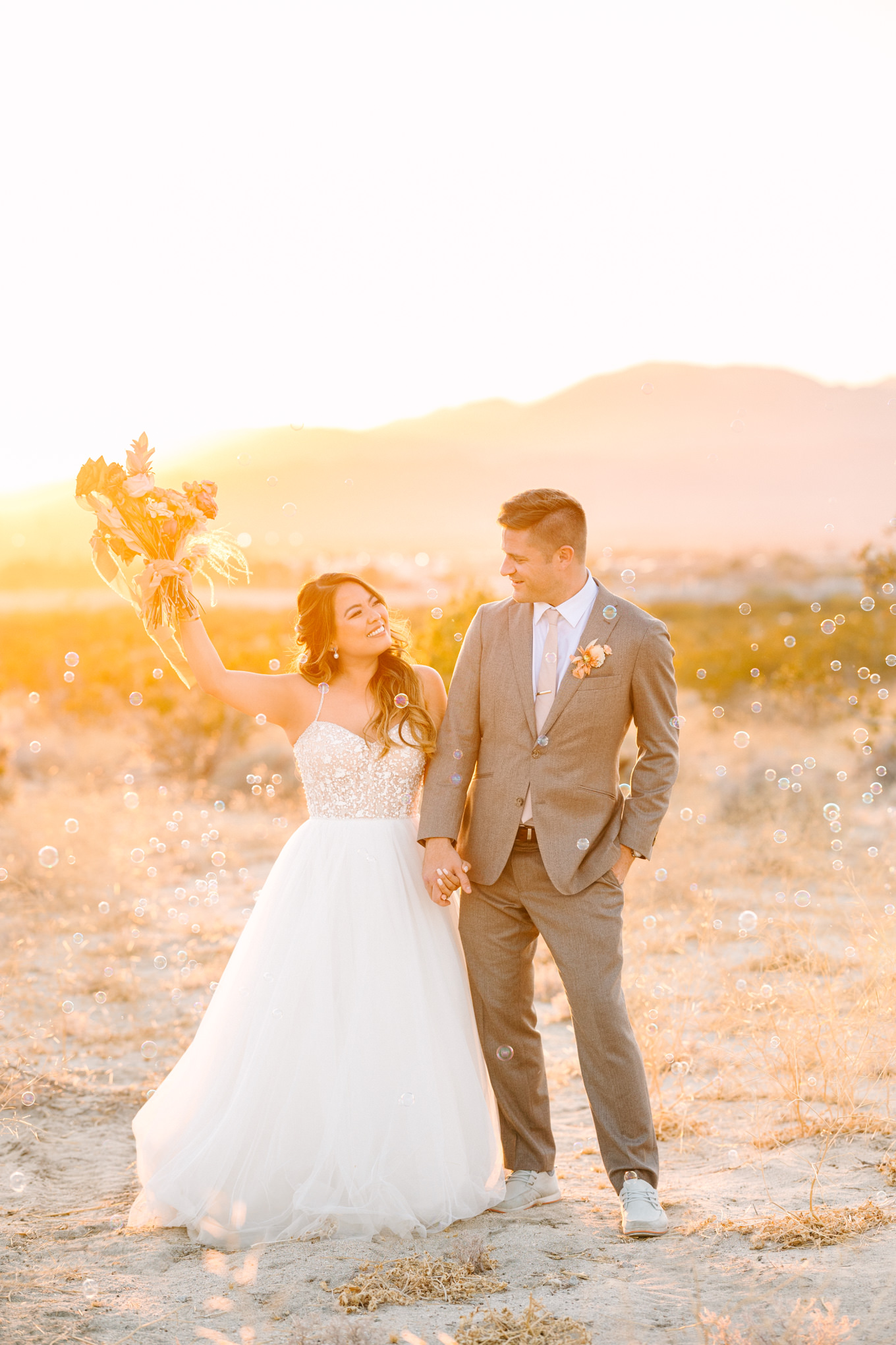 Bride and groom at sunset surrounded by bubbles | Pink and orange Lautner Compound wedding | Colorful Palm Springs wedding photography | #palmspringsphotographer #palmspringswedding #lautnercompound #southerncaliforniawedding  Source: Mary Costa Photography | Los Angeles