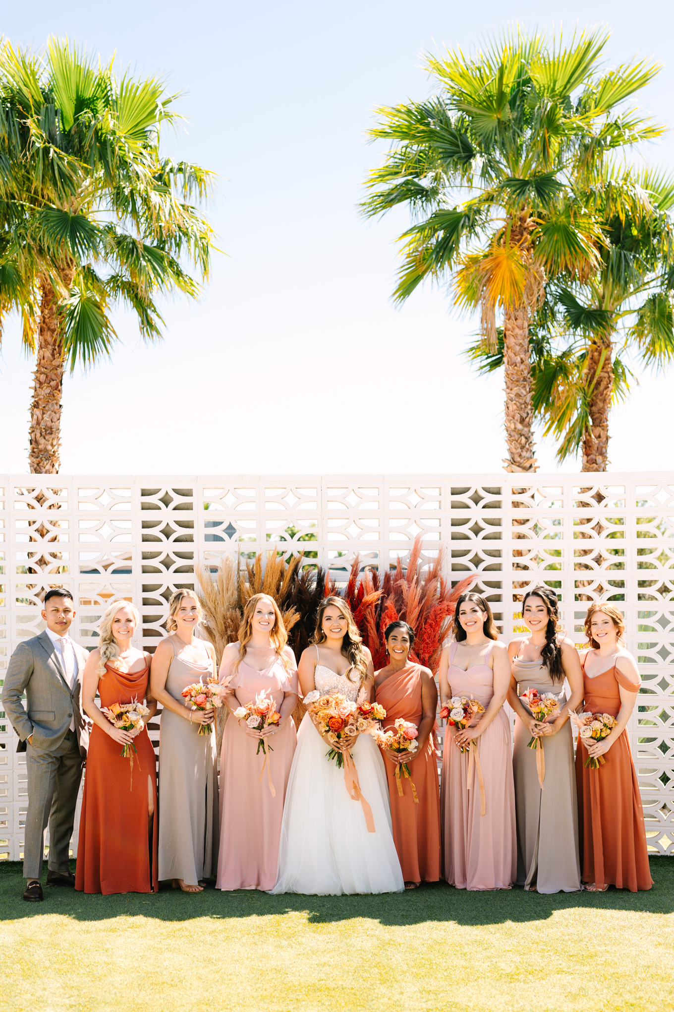 Bridal party on breeze block wall | Pink and orange Lautner Compound wedding | Colorful Palm Springs wedding photography | #palmspringsphotographer #palmspringswedding #lautnercompound #southerncaliforniawedding  Source: Mary Costa Photography | Los Angeles