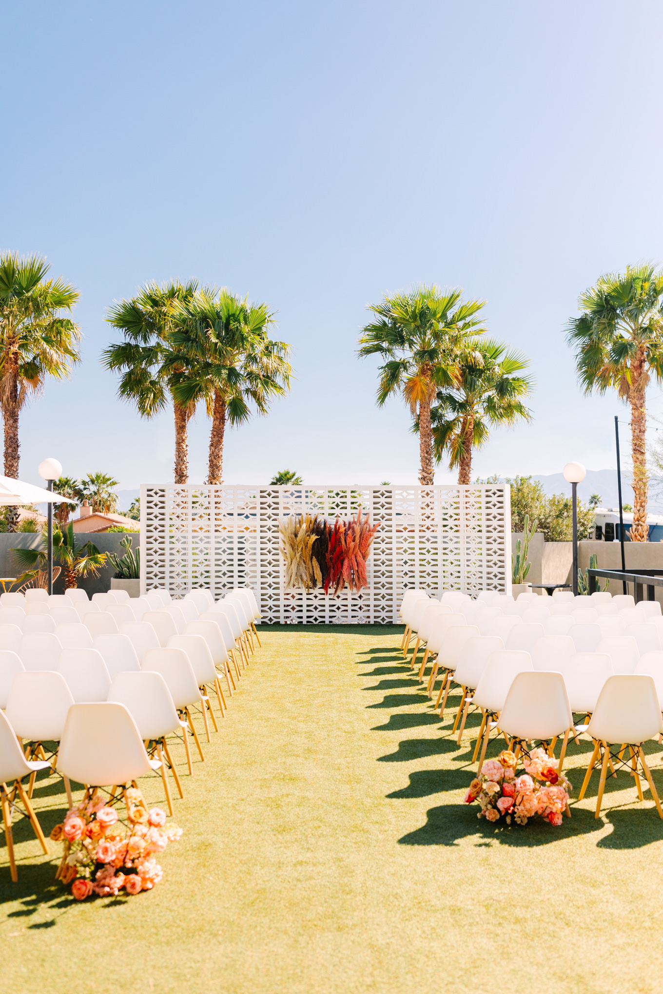 Colorful ceremony site with palm trees | Pink and orange Lautner Compound wedding | Colorful Palm Springs wedding photography | #palmspringsphotographer #palmspringswedding #lautnercompound #southerncaliforniawedding  Source: Mary Costa Photography | Los Angeles