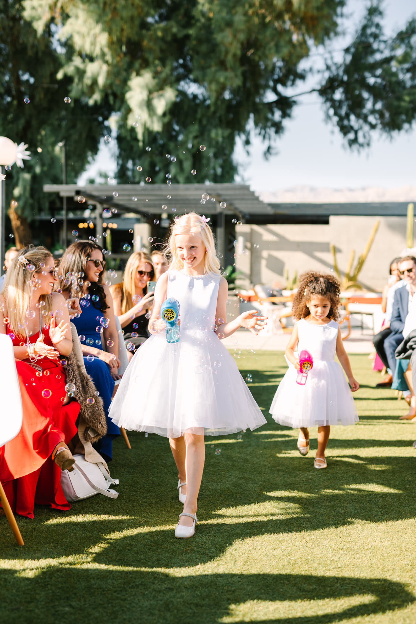 Flower girls with bubble guns | Pink and orange Lautner Compound wedding | Colorful Palm Springs wedding photography | #palmspringsphotographer #palmspringswedding #lautnercompound #southerncaliforniawedding  Source: Mary Costa Photography | Los Angeles