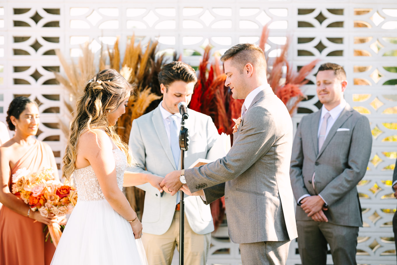Exchanging rings at wedding ceremony | Pink and orange Lautner Compound wedding | Colorful Palm Springs wedding photography | #palmspringsphotographer #palmspringswedding #lautnercompound #southerncaliforniawedding  Source: Mary Costa Photography | Los Angeles