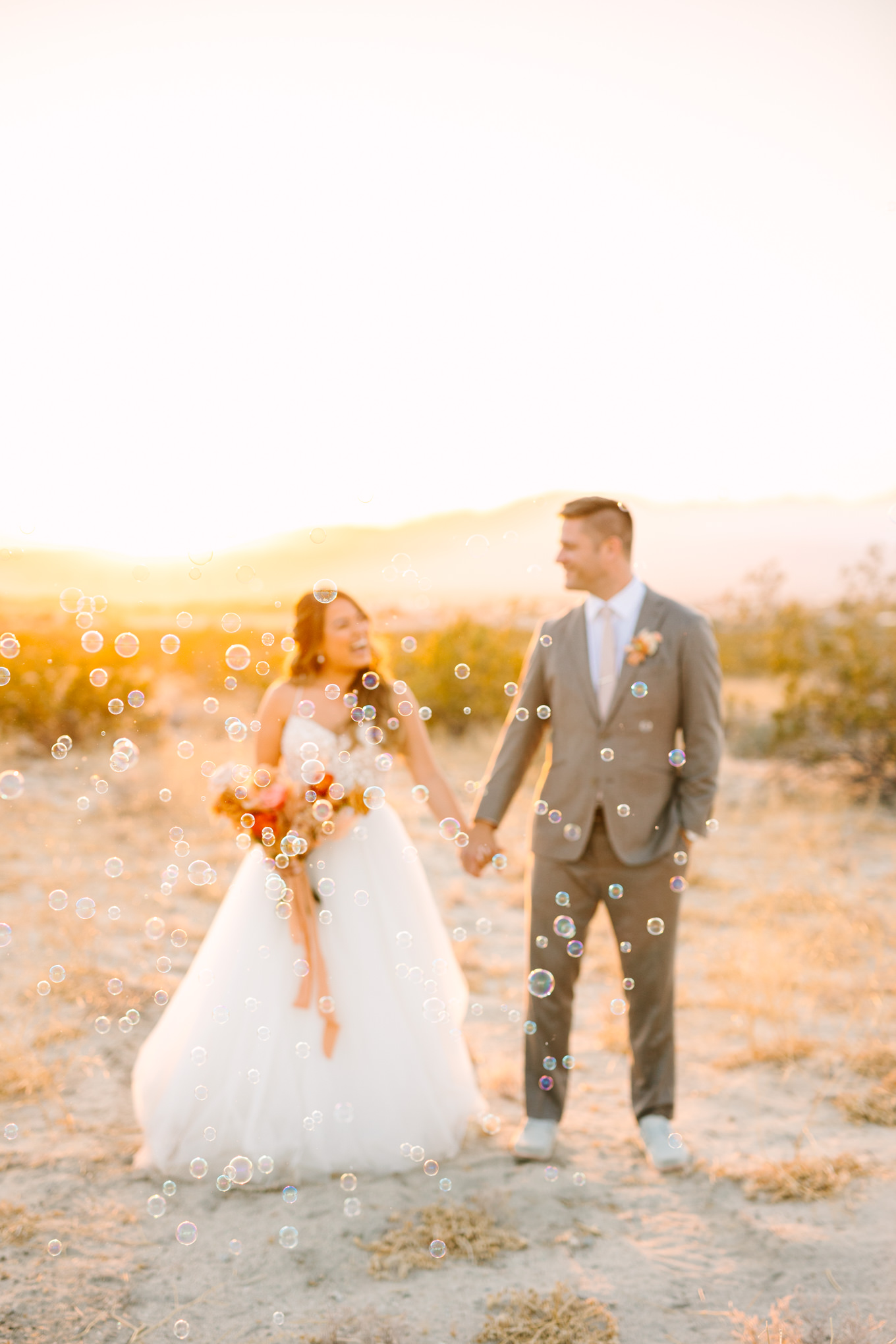 Bride and groom surrounded by bubbles at sunset | Pink and orange Lautner Compound wedding | Colorful Palm Springs wedding photography | #palmspringsphotographer #palmspringswedding #lautnercompound #southerncaliforniawedding  Source: Mary Costa Photography | Los Angeles