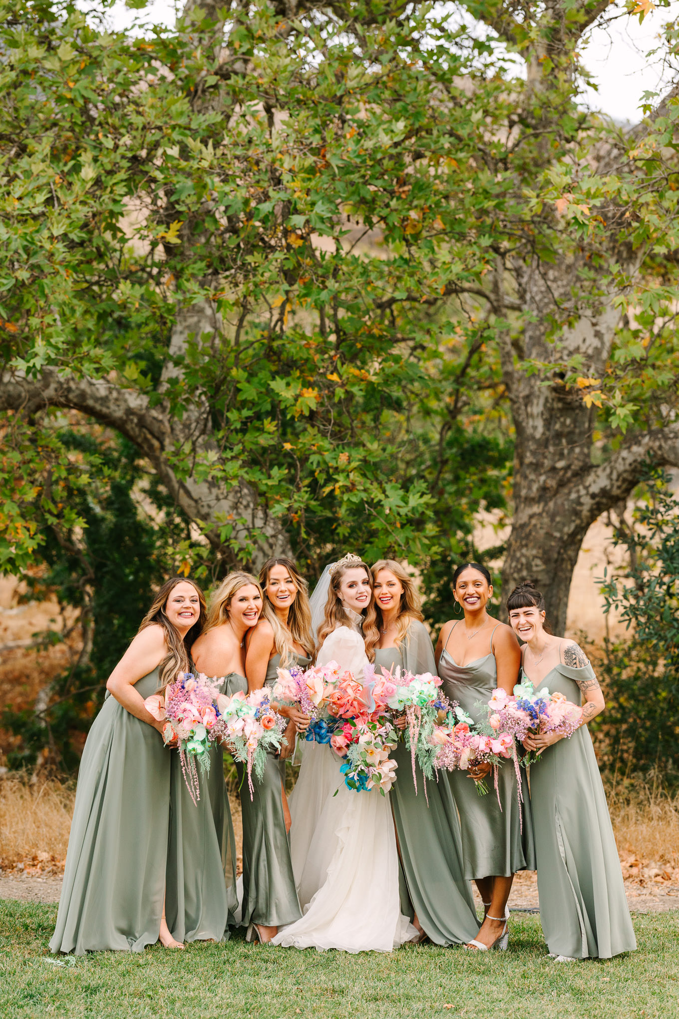 Bridesmaids in sage green gowns with colorful bouquets | Colorful and quirky wedding at Higuera Ranch in San Luis Obispo | #sanluisobispowedding #californiawedding #higueraranch #madonnainn   Source: Mary Costa Photography | Los Angeles